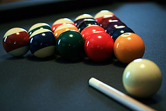 Glossy billiards balls and cue on table